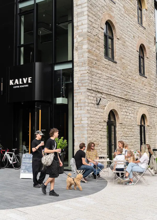 People sitting outside a coffee shop with a stone building in the background