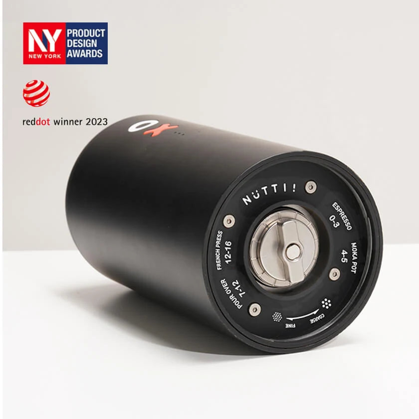 Black OX coffee grinder and a white table with grey backdrop